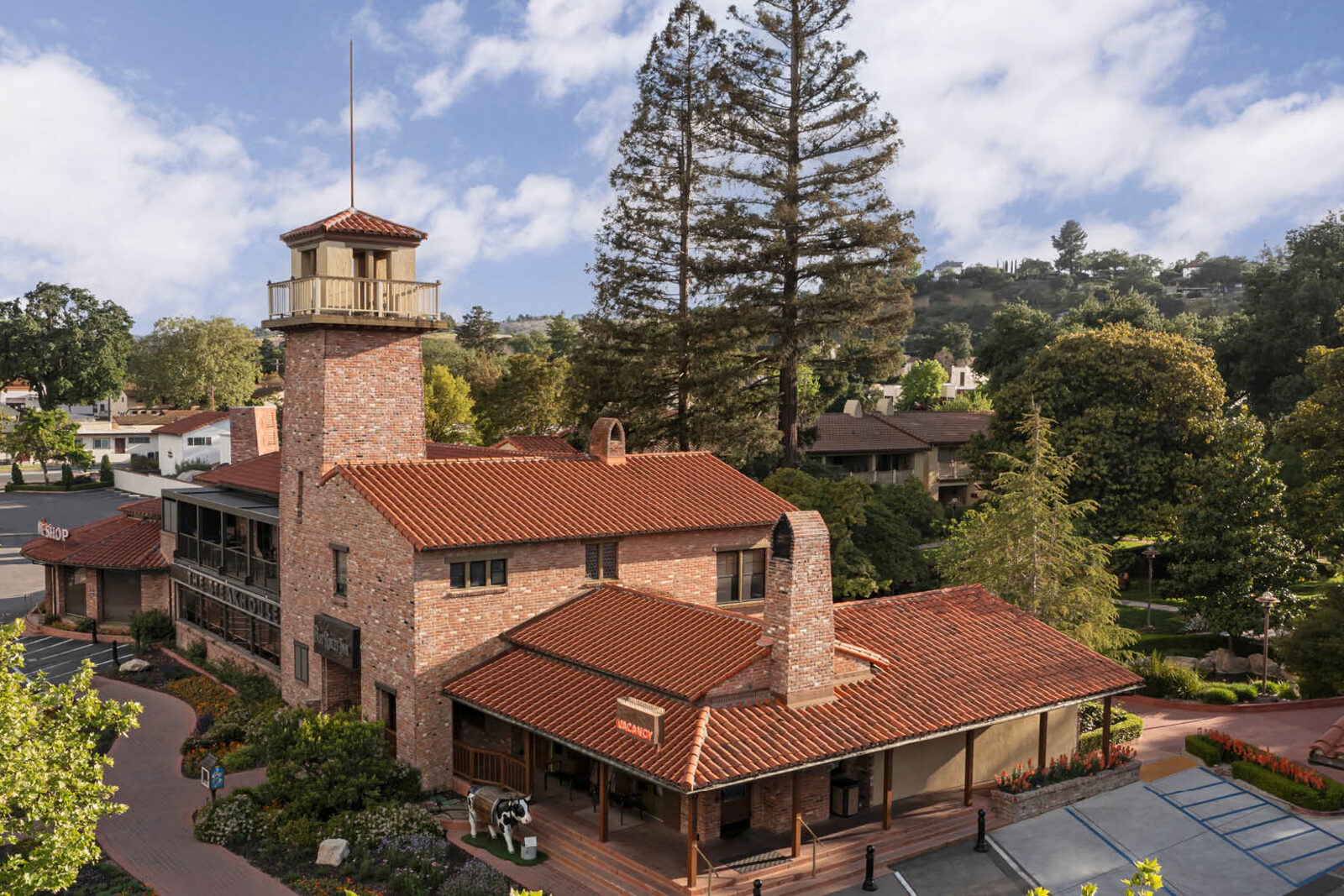 Aerial view of the historic Paso Robles Inn, its brick tower and tiled roofs among the trees