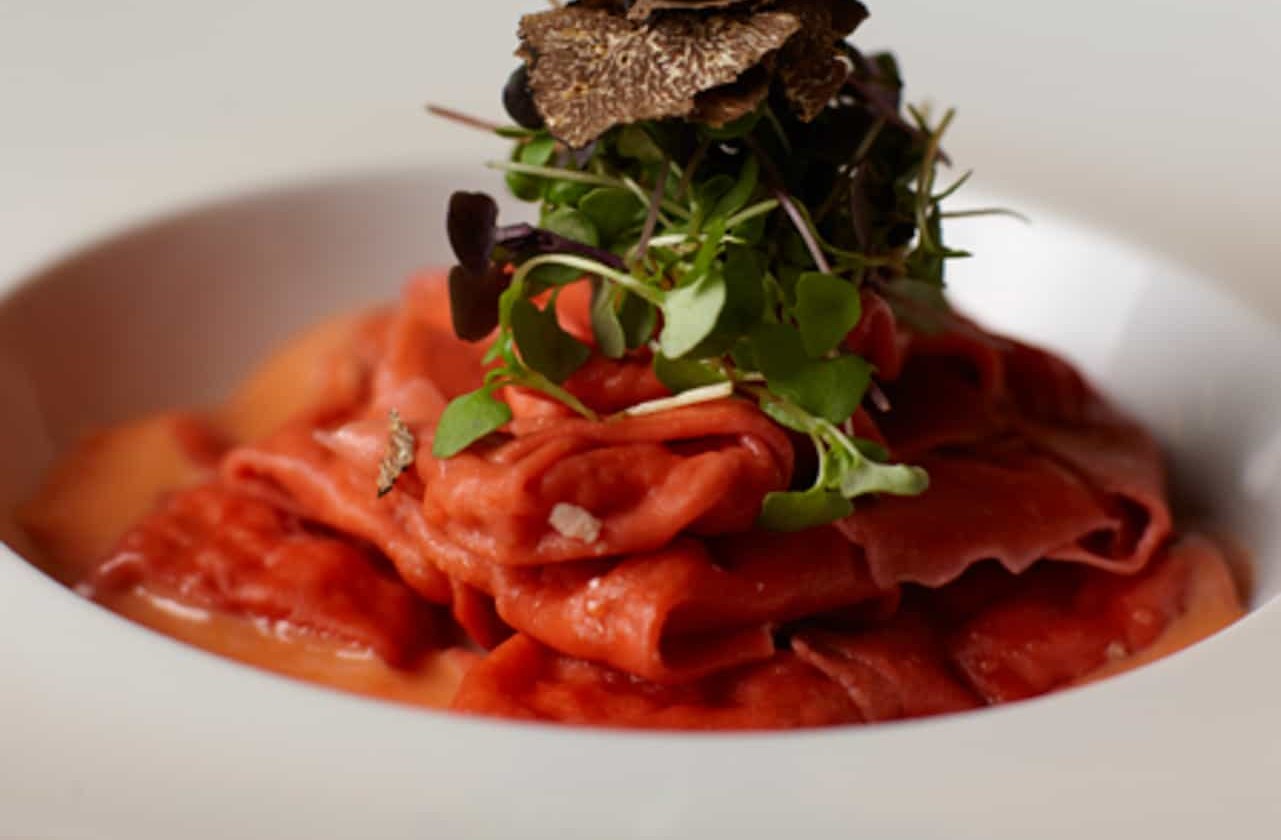 Handmade beet pasta plated with truffle and microgreens at Il Cortile Ristorante